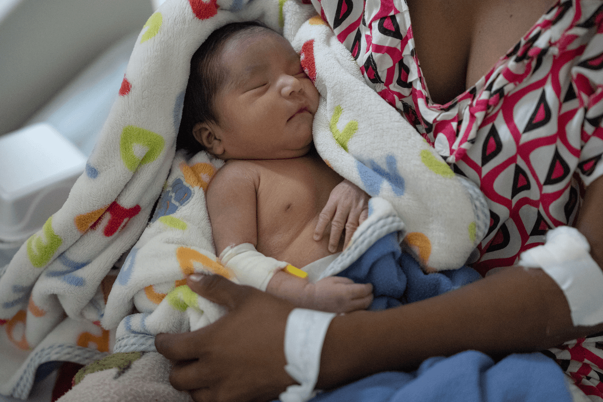 En nyfödd bebis ligger i armarna p�å sin mamma