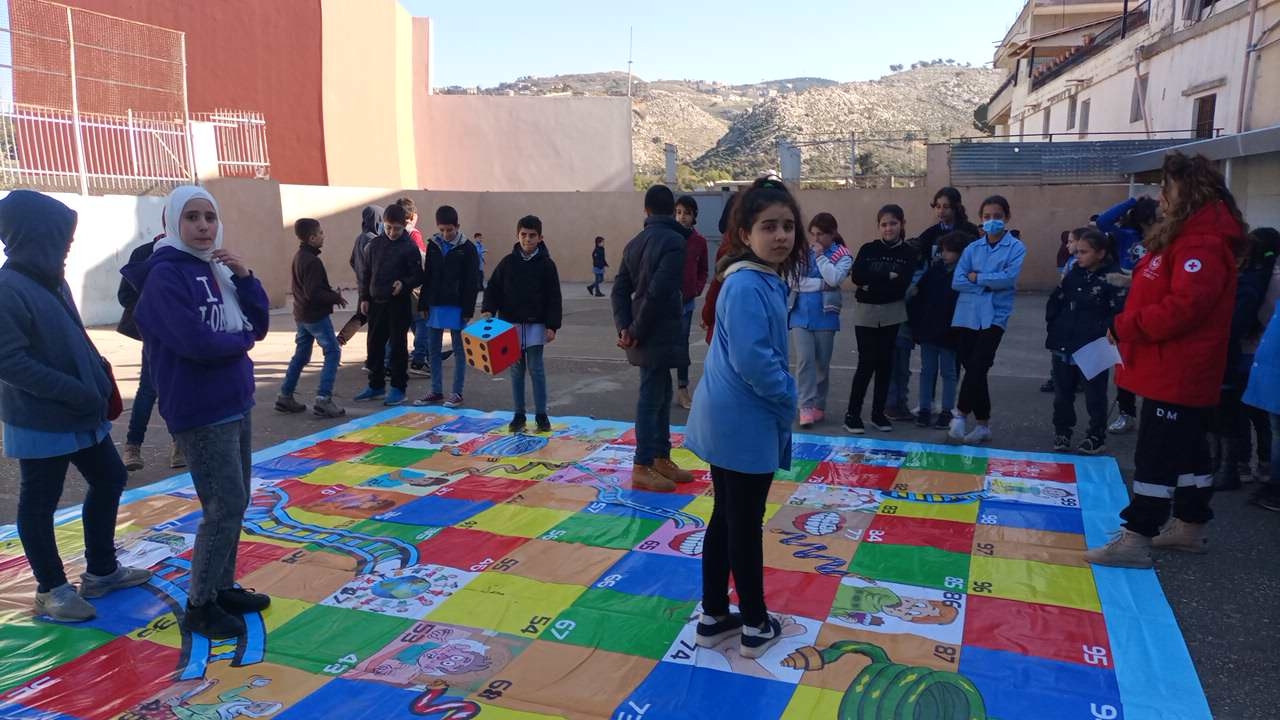 Elever står på rutor i olika färger på en skolgård.