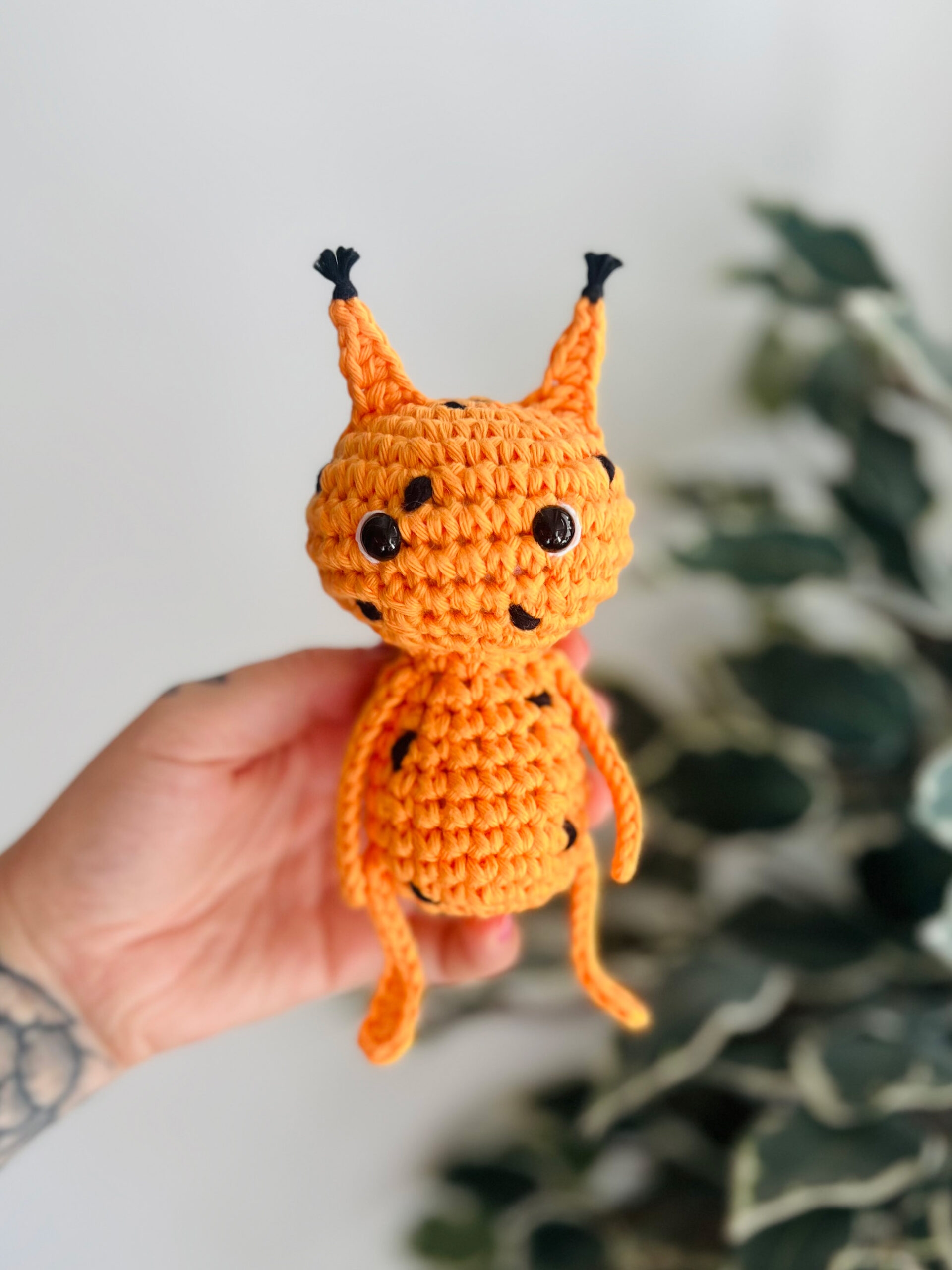 En hand håller en orange virkad figur