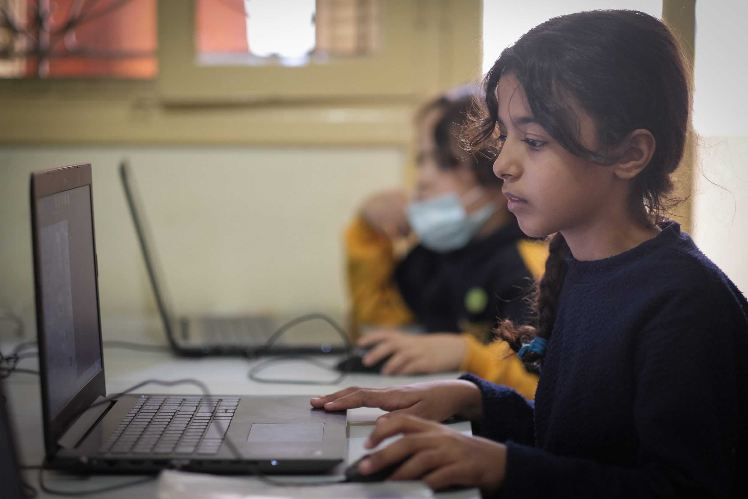 En flicka sitter framför en dator.