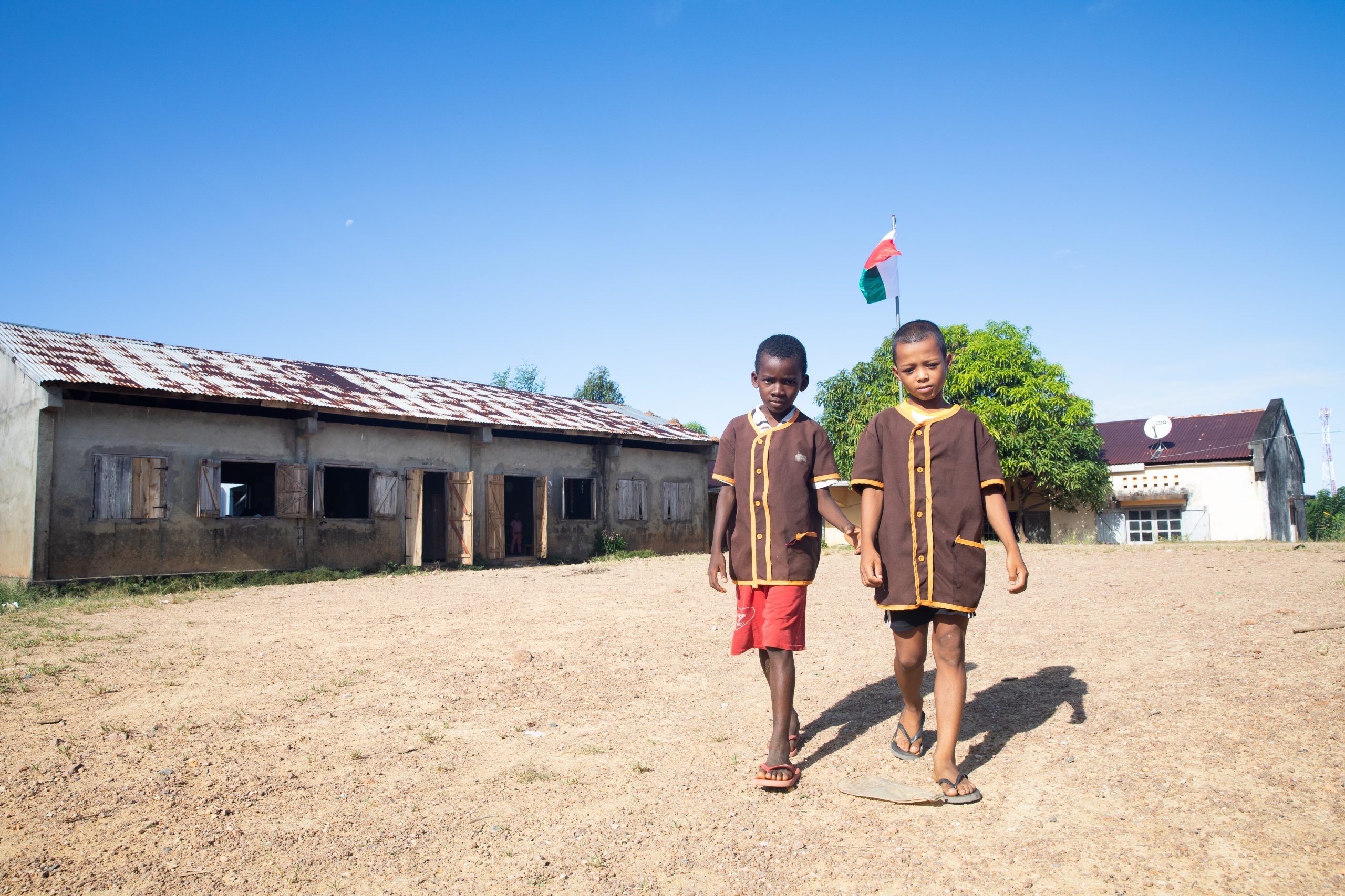 Två pojkar promenerar framför en skolbyggnad.