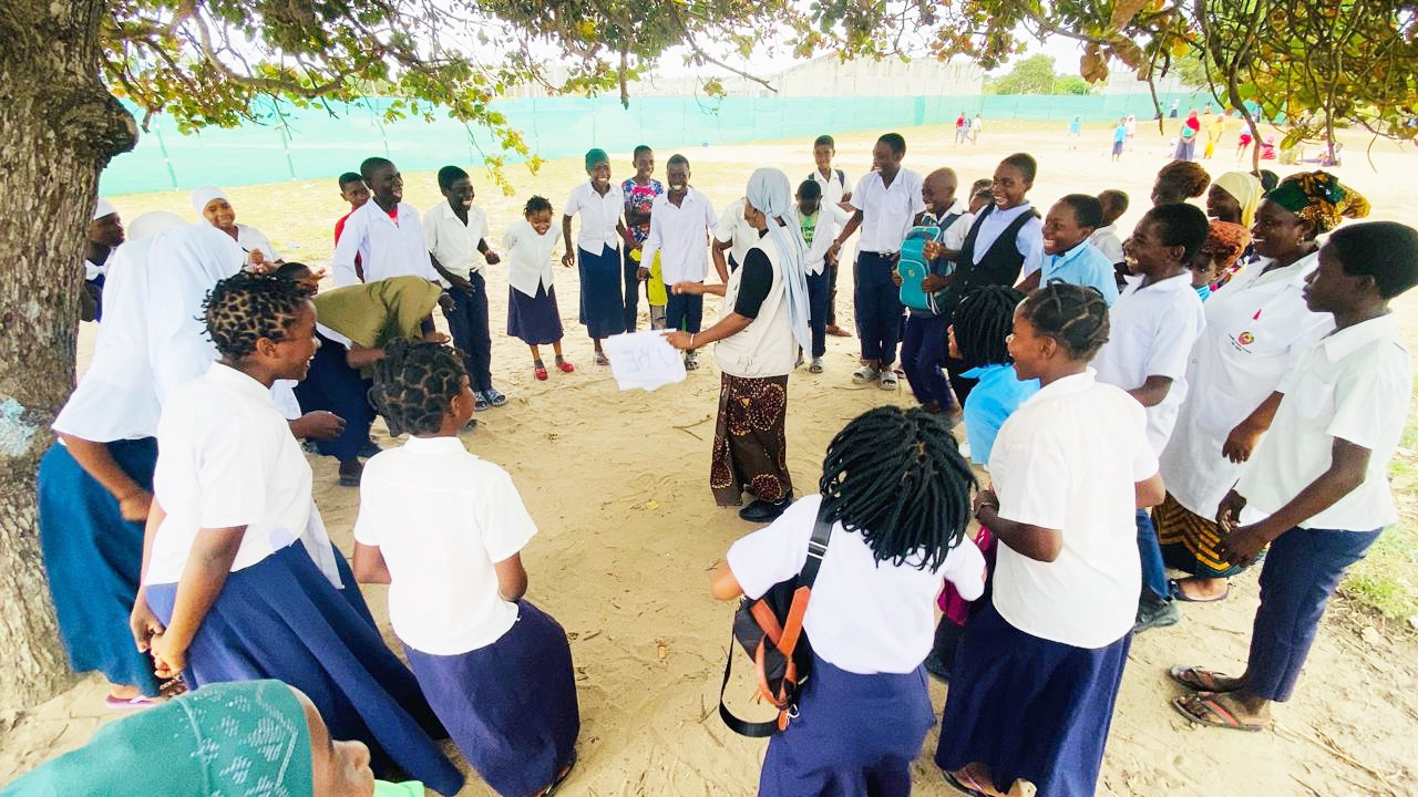 En grupp med barn står runt en kvinna som pratar