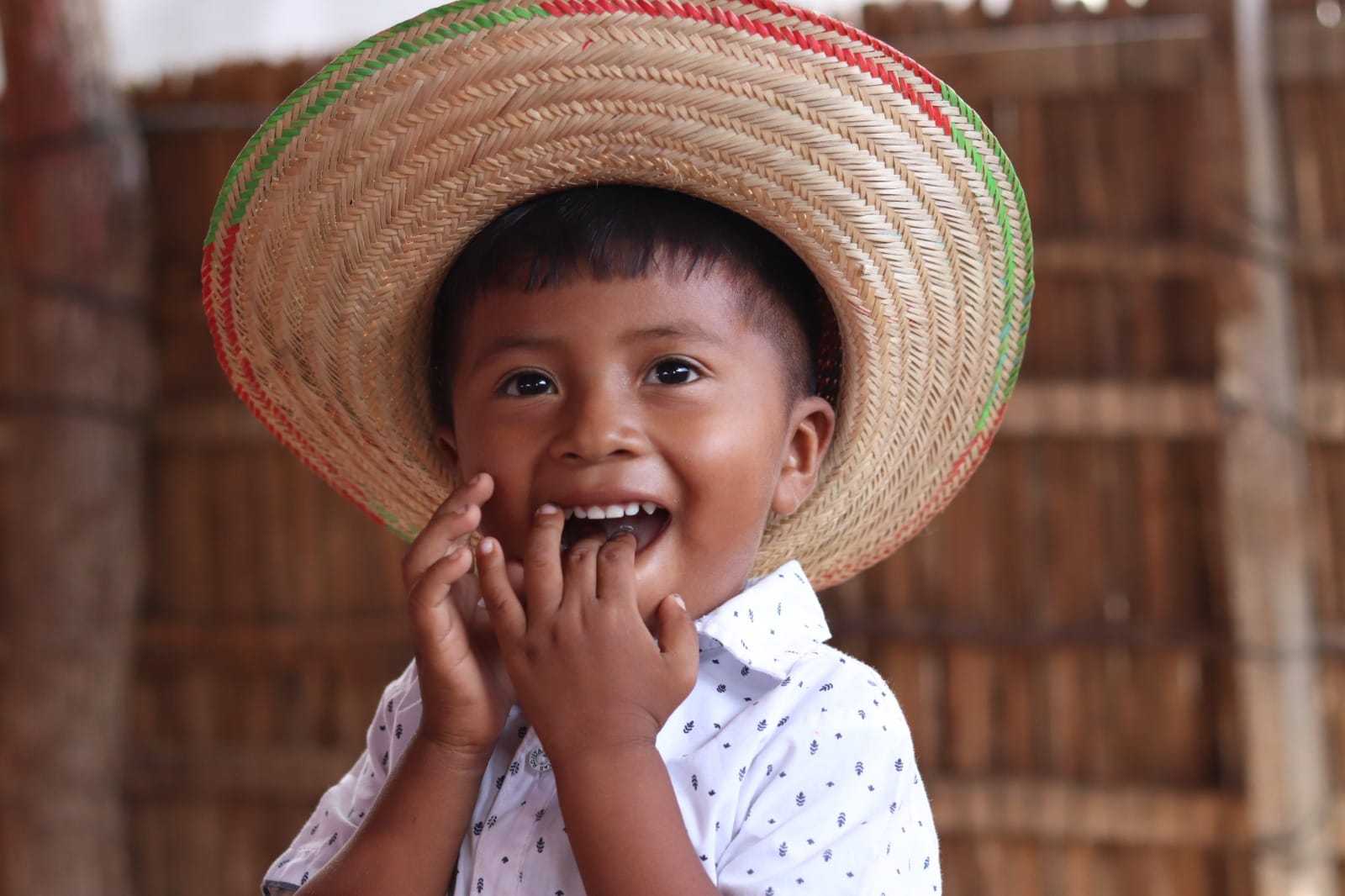 En pojke i stråhatt ler mot kameran