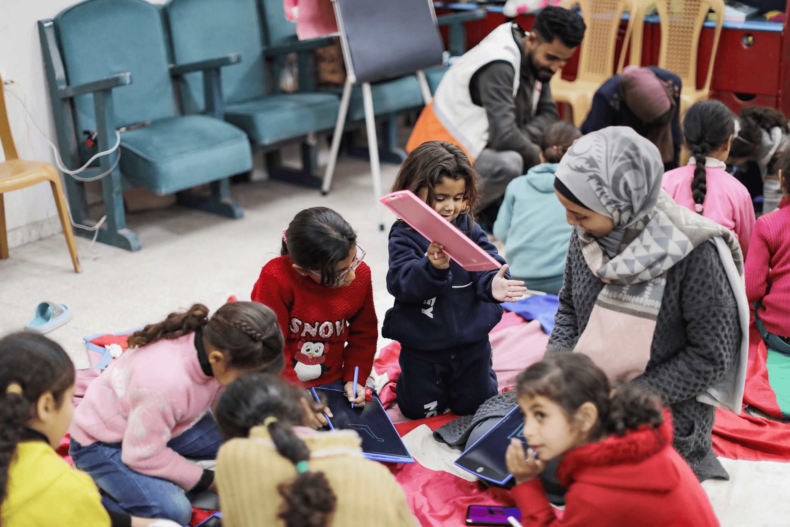 Flera barn sitter på golvet och pysslar.